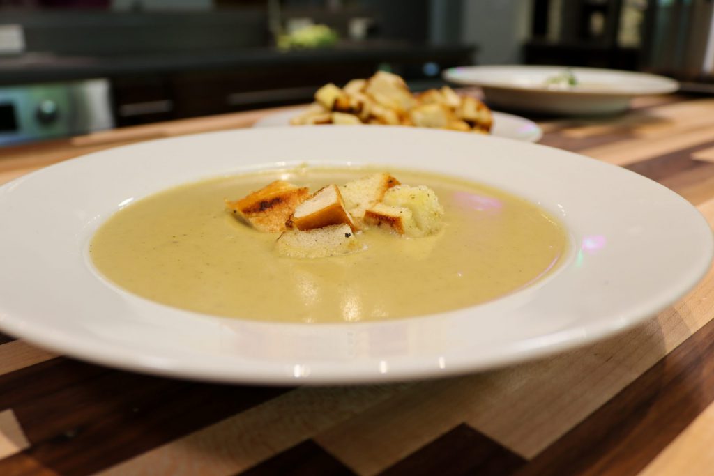 Broccoli Soup in the white deep plate, with croutons on the top in the kitchen, side tail shot