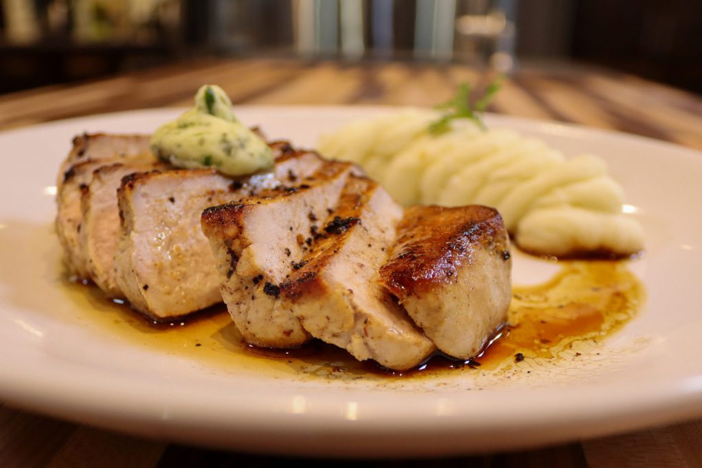 Sliced Pork Chop Steak Vepřová Kotleta served with mashed potatoes on the white plate with the kitchen in the background