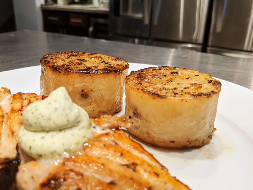 Fondant Potatoes Recipe in detail on the plate with kitchen in the background