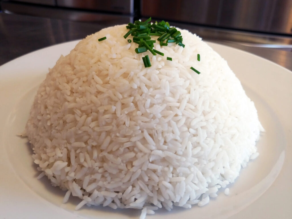 Freshly cooked rice on the plate decorated with herbs, side close up shot.
