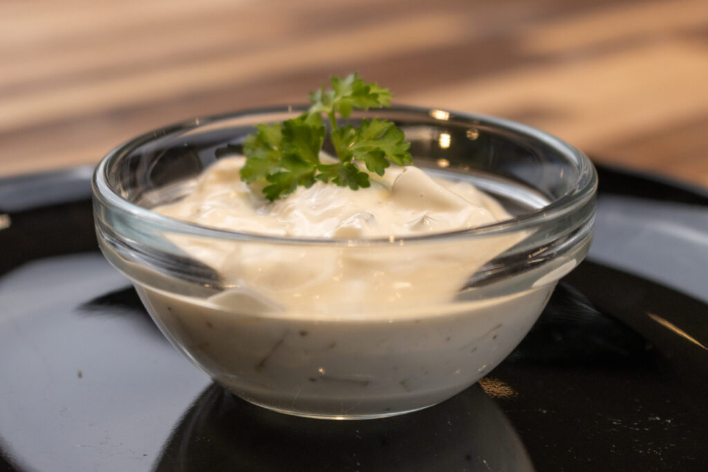 Czech Tartar Sauce Tatarka Recipe in the small bowl on the black plate, medium distance side shot