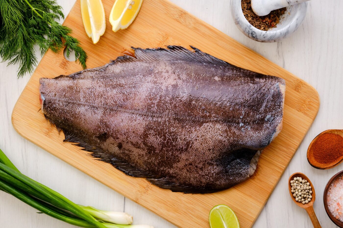 Top view of raw fresh halibut without head on wooden cutting board