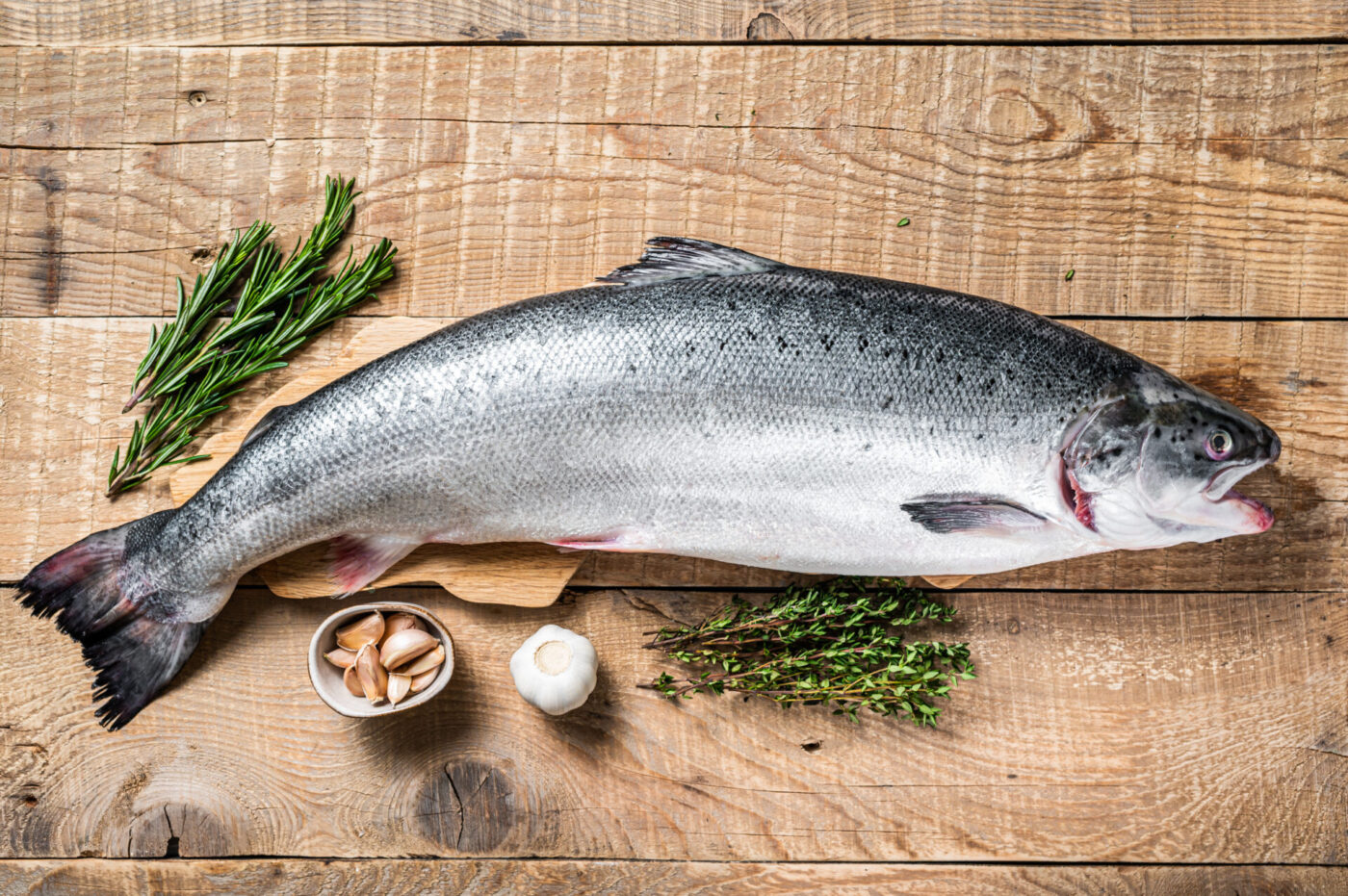 Raw marine salmon fish on a  wooden kichen table with herbs