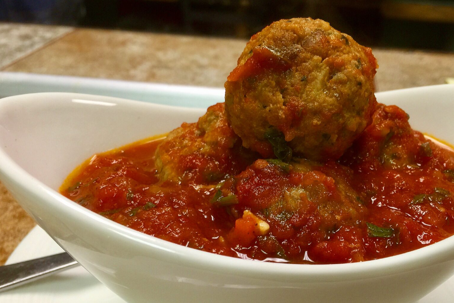 Beef, Pork, and Ricotta Meatballs with Polenta in white bowl, detail shot