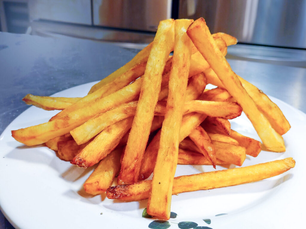 Homemade French Fries on the white plate, on the stainless table