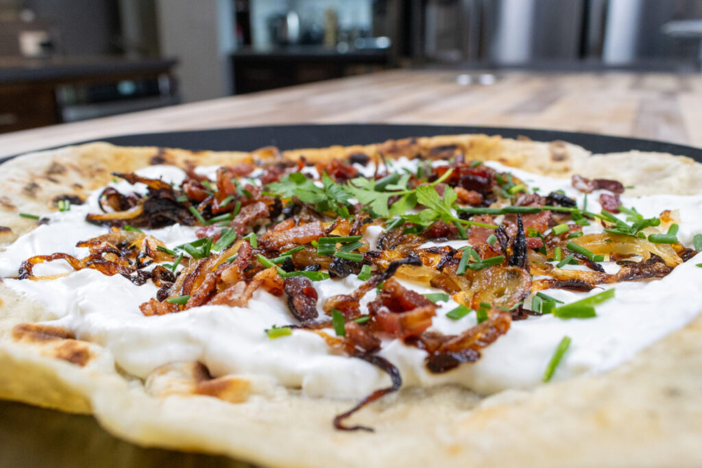 Lokše flatbread with bryndza cheese substitute and bacon, on the black plate, super detail to the center of the plate