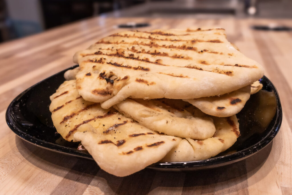 Garlic Naan Bread Recipe on the black plate, close up shot with the kitchen in the background