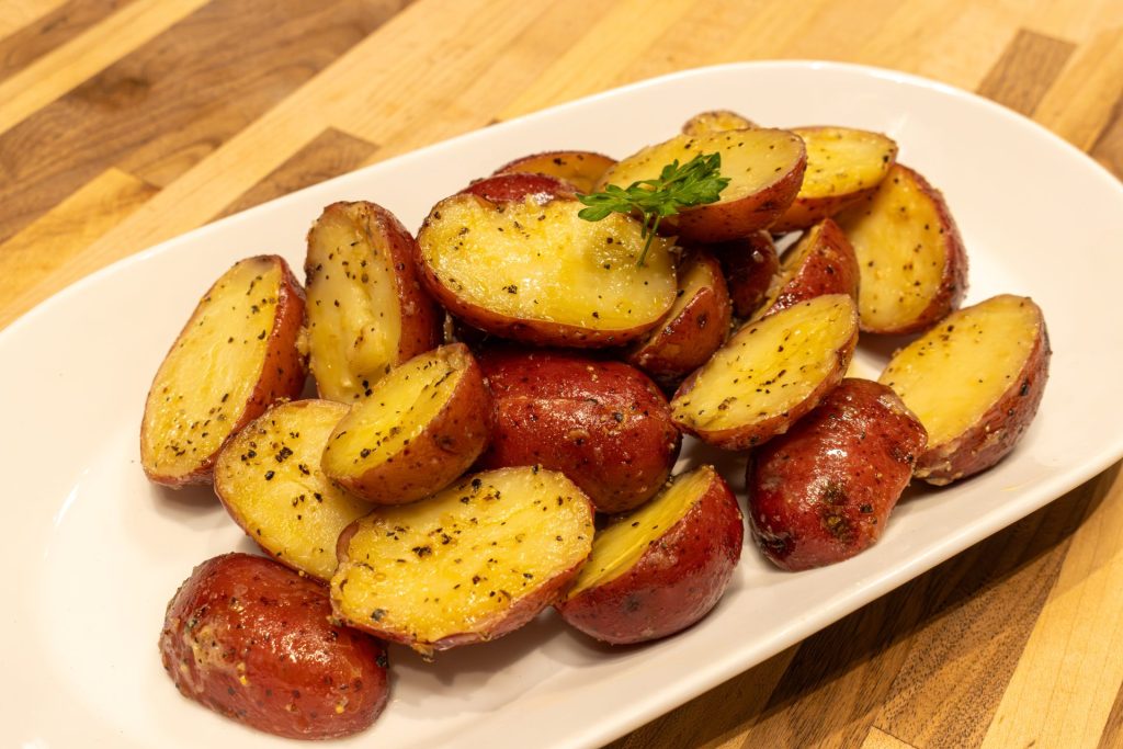 Baby Red Potatoes with Butter on the white oval plate, different supper close up shot
