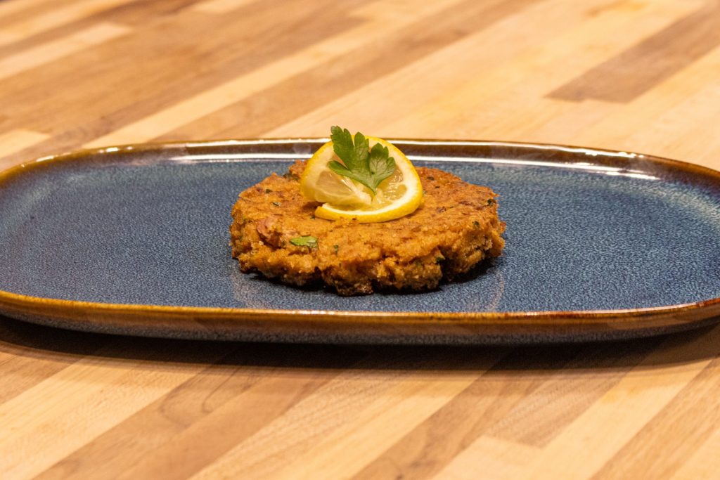 Tuna Cakes: Tuna cake with lemon on the blue oval plate, side close up shot