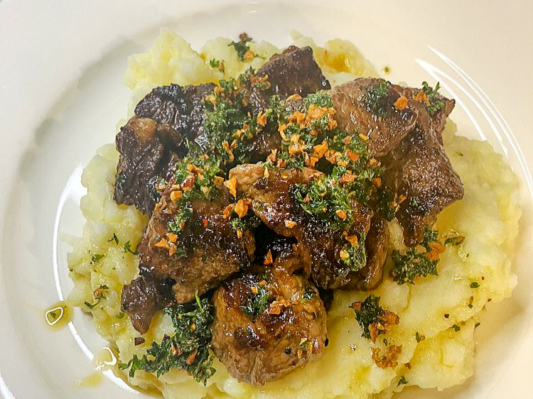 Close up shot to Sauce for Burnt Garlic Steak Bites on mashed potatoes, the close up view on the plate.