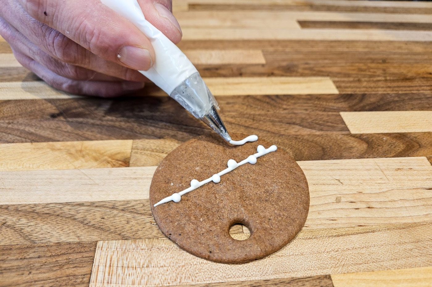 Demonstration of how to decorate gingerbread cookies as round ornaments.