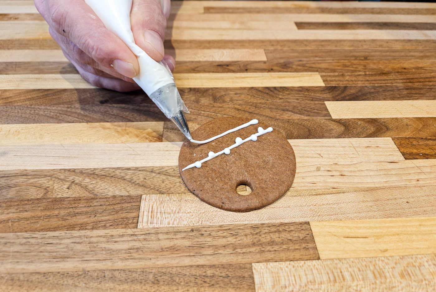 Demonstration of how to decorate gingerbread cookies as round ornaments.