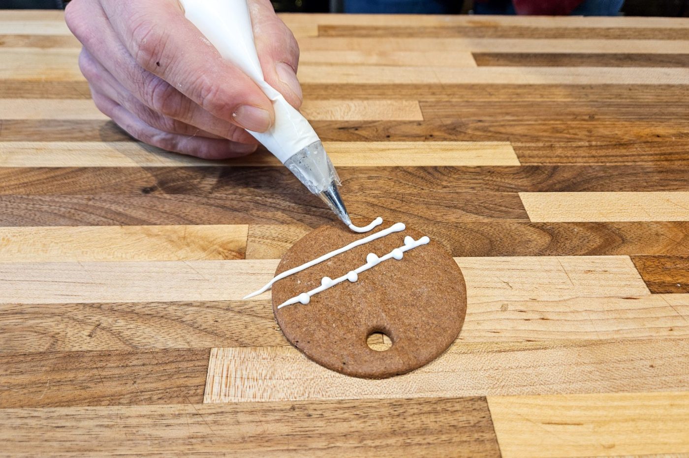 Demonstration of how to decorate gingerbread cookies as round ornaments.