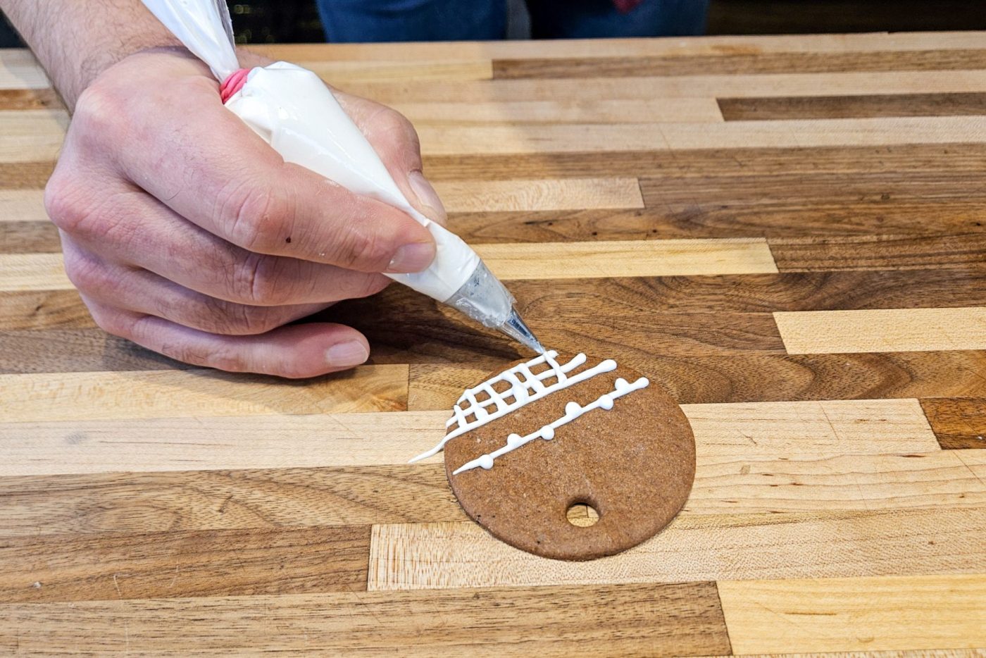 Demonstration of how to decorate gingerbread cookies as round ornaments.