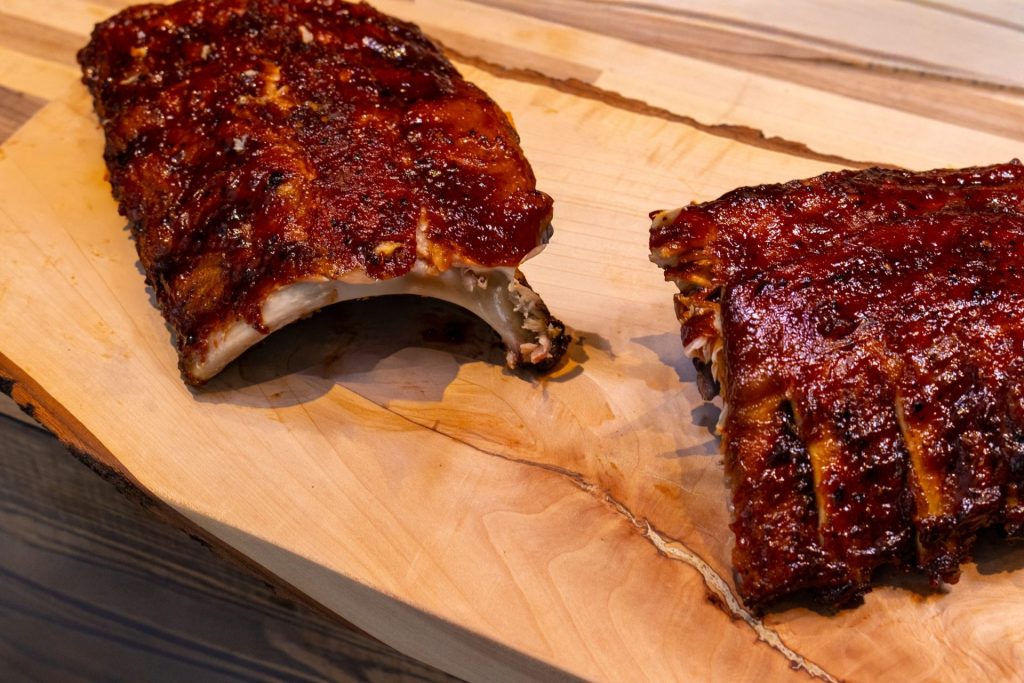American BBQ - Honey Pork Ribs on the rustic wooden cutting board , cut in halve, close up side shot
