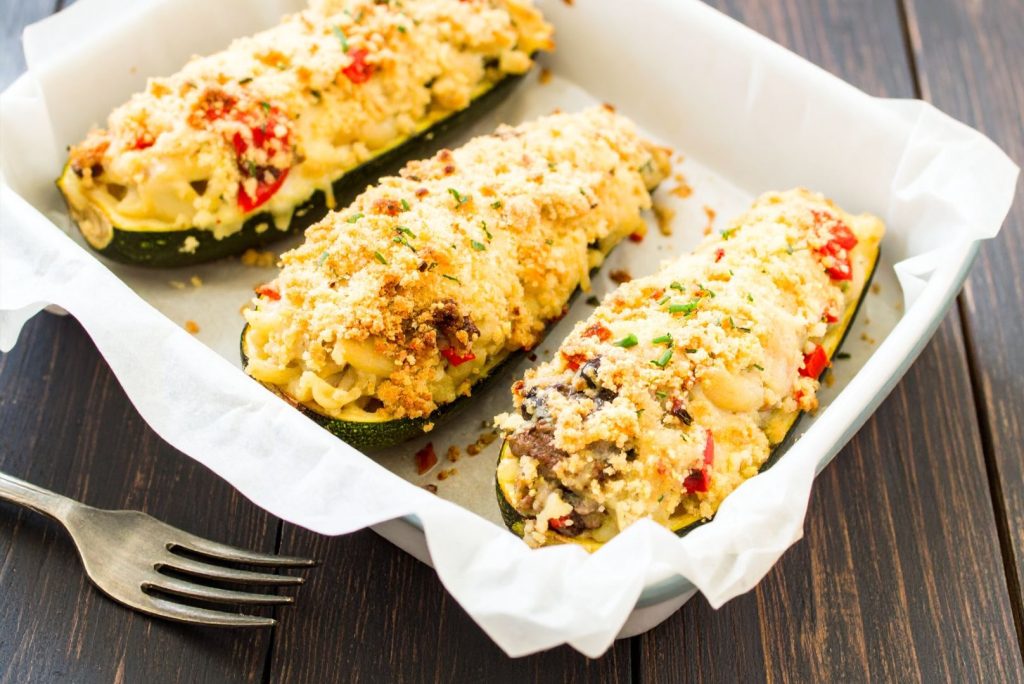Zucchini Stuffed with Macaroni and Cheese in the baking pan on the rustic table, top close up shot.