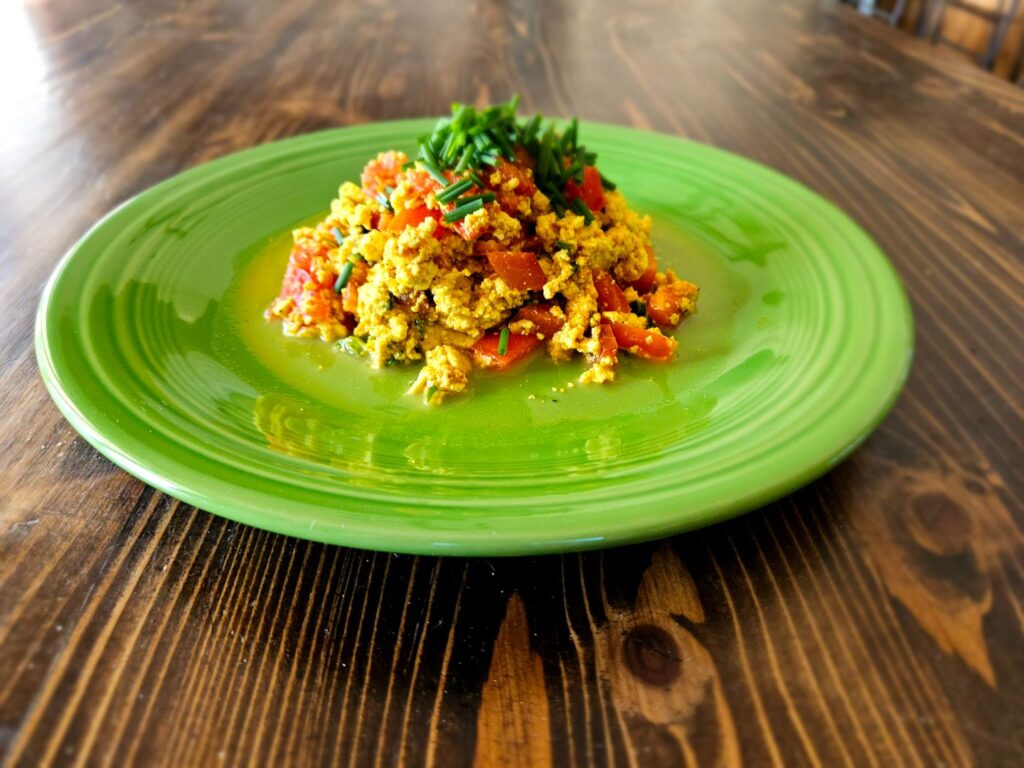 South Western Tofu Scramble on the green plate on the rustic table, medium distance side shot